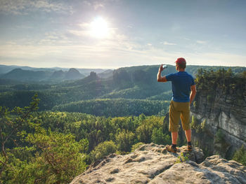 Rear view of man standing on mountain against sky