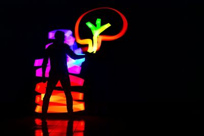 Silhouette person standing against illuminated light painting