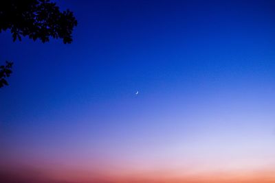 Low angle view of moon against clear blue sky
