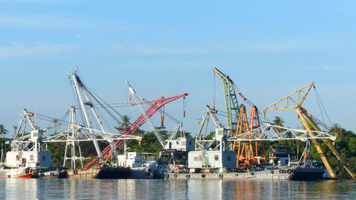 Cranes at commercial dock against sky