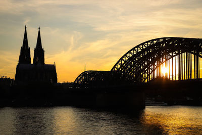 Arch bridge over river during sunset