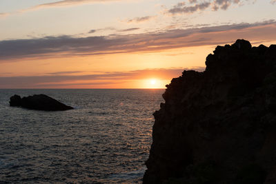 Rock formation on sea against sky during sunset