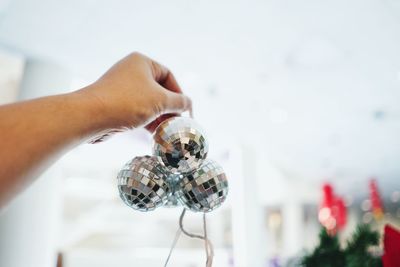 Cropped hand holding baubles at home