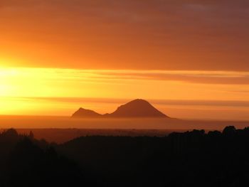 Scenic view of silhouette mountains against orange sky