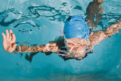 Low section of man swimming in pool