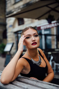 Portrait of confident young woman sitting on bench in city