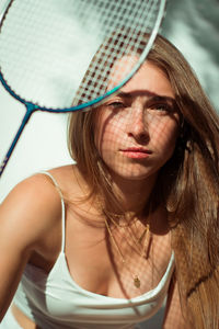 Close-up portrait of beautiful young woman holding racket