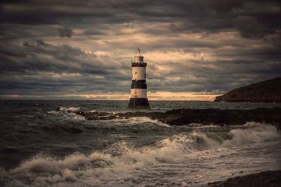 Lighthouse by sea against sky