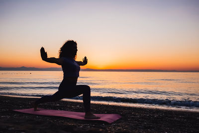 Silhouette woman standing at beach during sunset