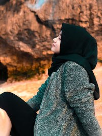 Midsection of woman sitting on rock