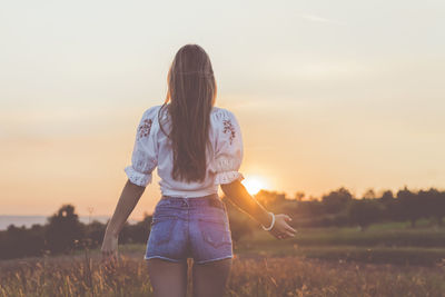 Rear view of senior woman standing in front of field