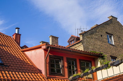 Vintage roofs of houses with windows, balconies and ventilation pipes against sky in old town