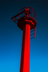 Low angle view of red windmill against clear blue sky