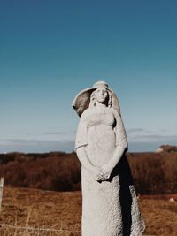 Rear view of man standing on rock against clear sky