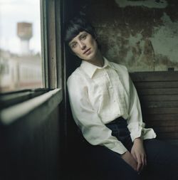 Portrait of young woman sitting on window