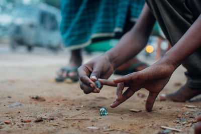 Close-up of hands playing with marbles outdoors