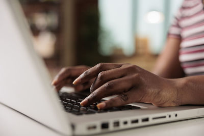 Midsection of woman using laptop at table