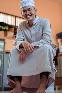 Portrait of a smiling young woman holding camera at home