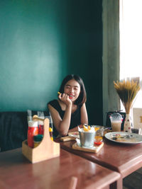 Portrait of a smiling young woman sitting on table