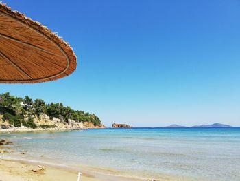 Scenic view of beach against clear blue sky