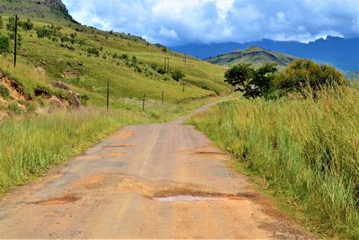 Road amidst field against sky