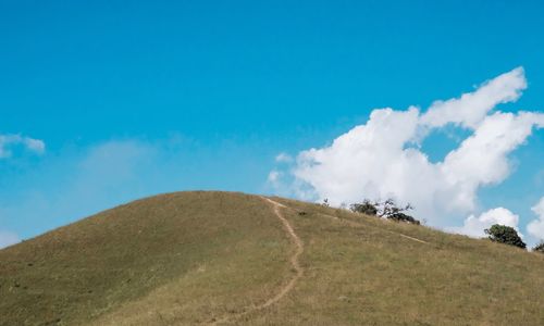 Low angle view of arid landscape against blue sky