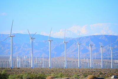 Wind turbines on field against blue sky