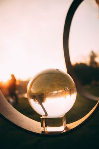 Close-up of crystal ball against sky during sunset