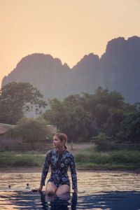 Full length portrait of woman on land against sky during sunset