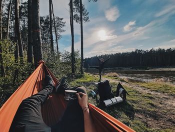 Low section of person in forest against sky