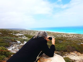 Rear view of woman photographing sea against sky along the great australian bight