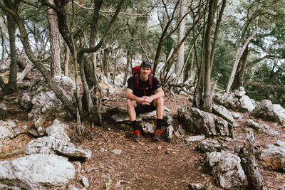 Young man sitting on rock in forest