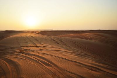 Scenic view of desert against clear sky during sunset