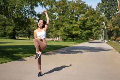 Full length of young woman jogging on road