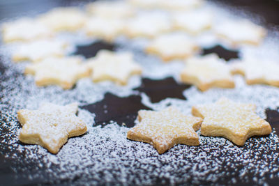 Powdered sugar above star shaped christmas cookies