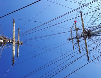 Low angle view of electricity pylon against blue sky