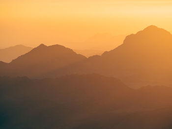 Scenic view of silhouette mountains against orange sky