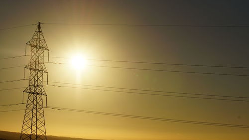 Low angle view of silhouette electricity pylon against sky during sunset