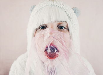 Close-up of woman in costume with pink plastic against wall