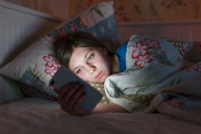 Portrait of young sleepy girl in a bed. woman can't sleep and using smartphone, suffer from insomnia