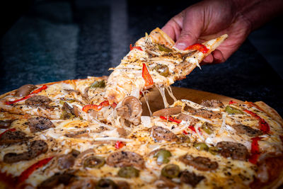 Close-up of hand holding pizza