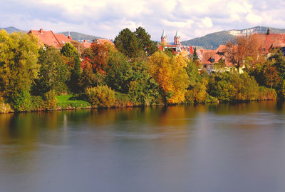 Scenic view of river neckar by trees and buildings against sky