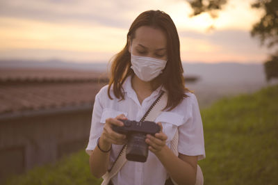 Young woman checking her camera in golden hour