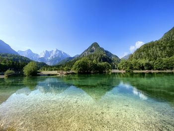 Scenic view of lake and mountains against blue sky