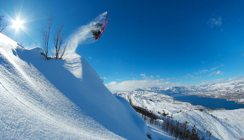 Downhill skier performing backflip from cliff.