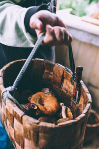 Midsection of person holding basket of mushrooms