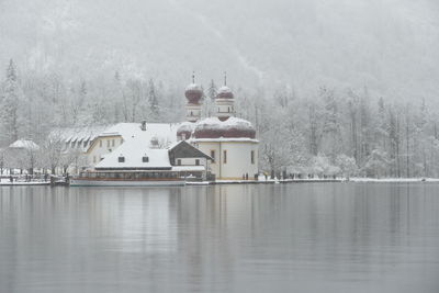 Built structure by lake against buildings during winter