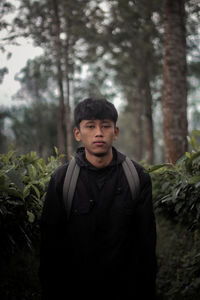 Portrait of young man standing in forest