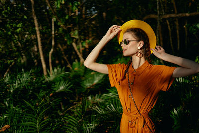 Young woman looking away while standing on tree