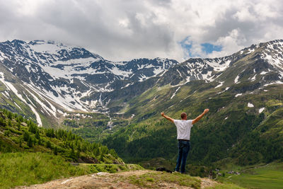 Rear view of man standing on mountain against sky